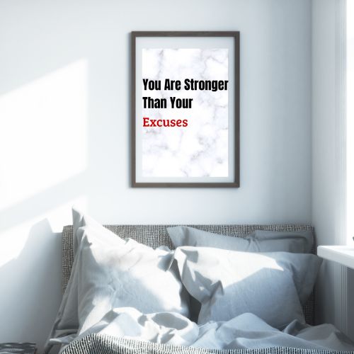 Framed motivational poster on a wall above a bed with white bedding.